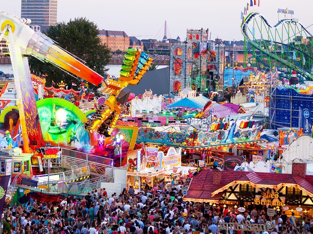 Luftiger Blick auf einen Jahrmarkt mit Karussells, Achterbahn und Essenszelten