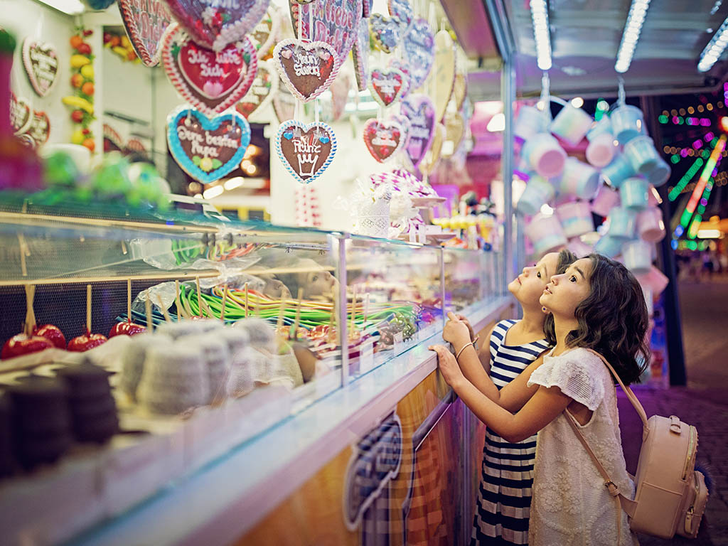 Kleine Mädchen machen große Augen am Süßwarenstand auf einem Volksfest